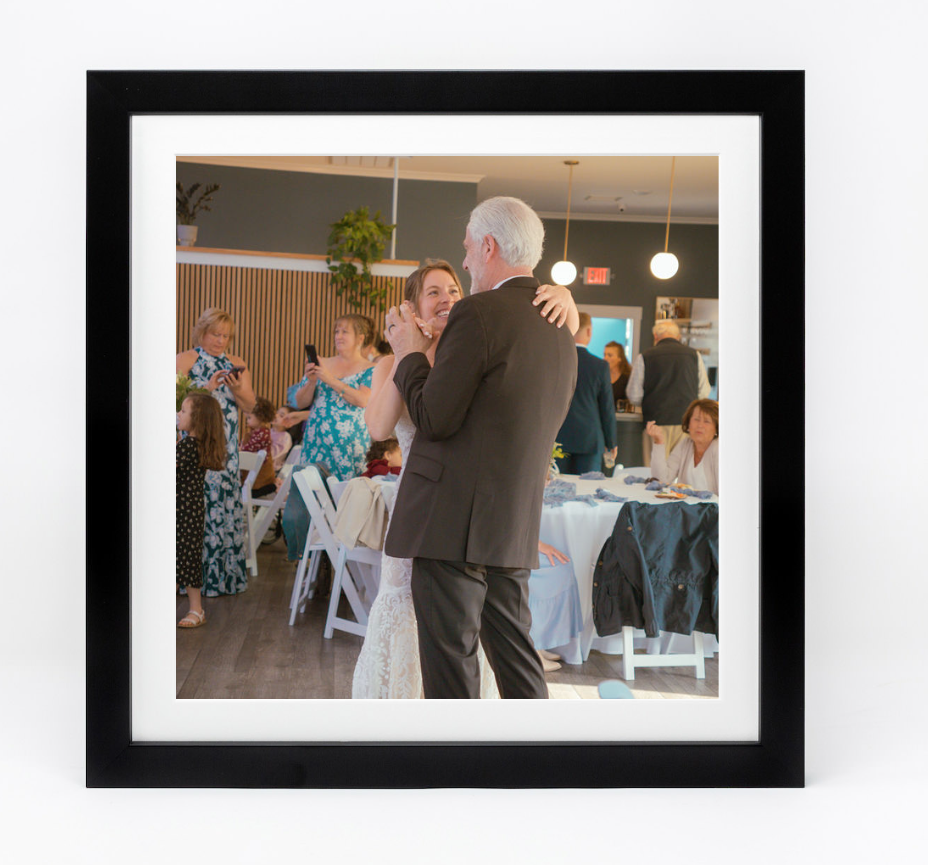 Social gathering with people dancing in reception hall with white chairs.