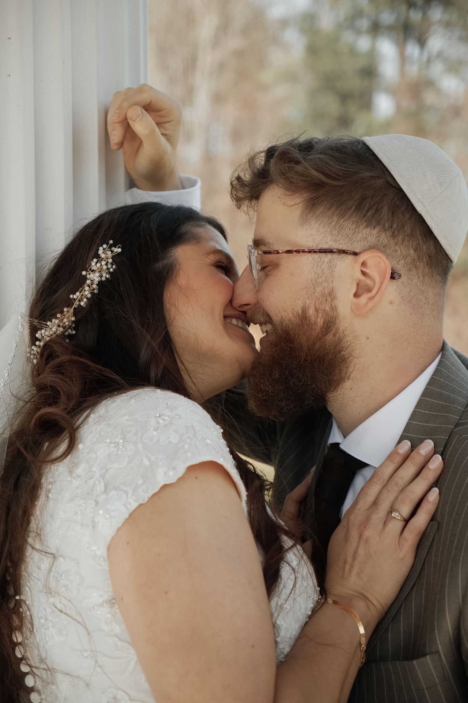Intimate wedding portrait of couple sharing a close moment with bride wearing crystal hair accessory.