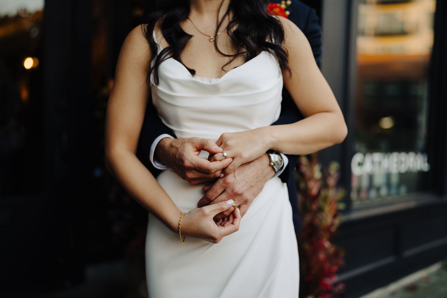 Close-up of hands in white dress adjusting jewelry or accessories.