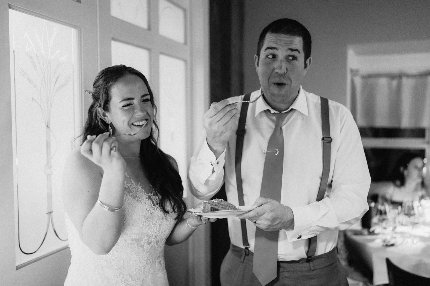 A candid black and white moment of a couple sharing dessert at their wedding reception.