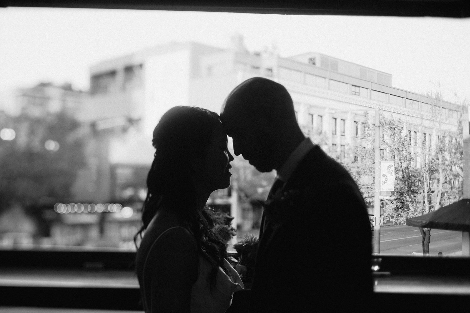 Silhouetted couple sharing an intimate moment against urban backdrop.