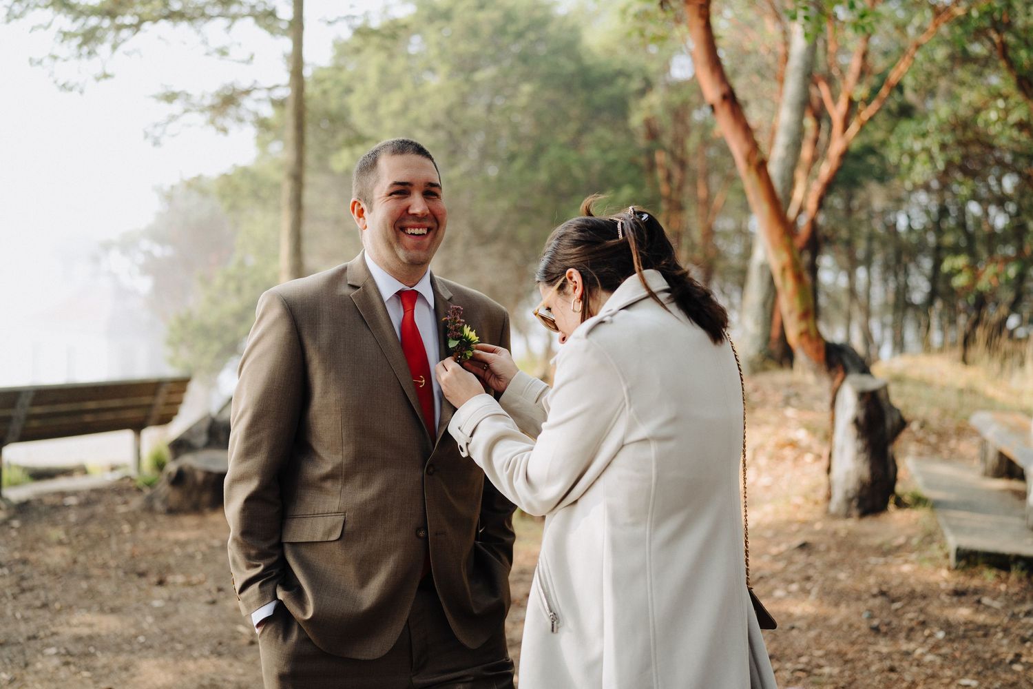 Couple shares candid moment during outdoor forest photoshoot on misty mountainside.
