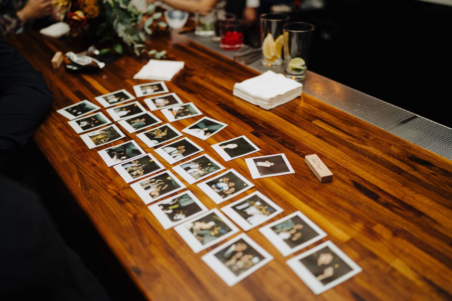 Collection of polaroid-style photos arranged on wooden table at wedding reception.