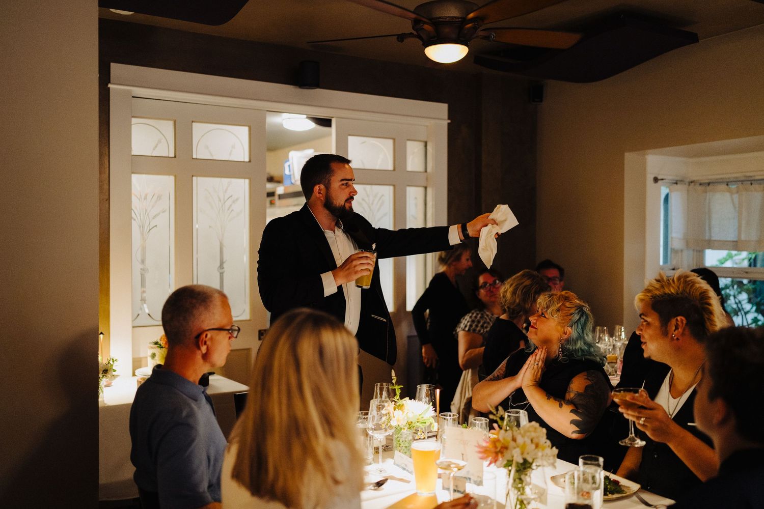 Wedding guests gathered around an elegantly set dining table during a reception celebration.