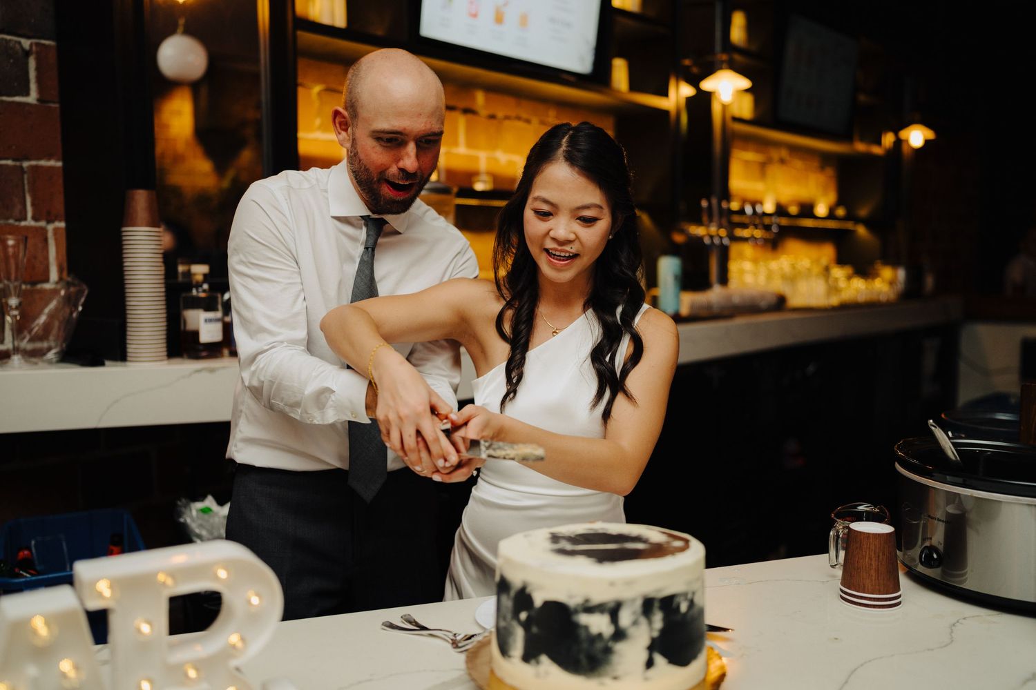 Couple cutting their black and white wedding cake together at reception.
