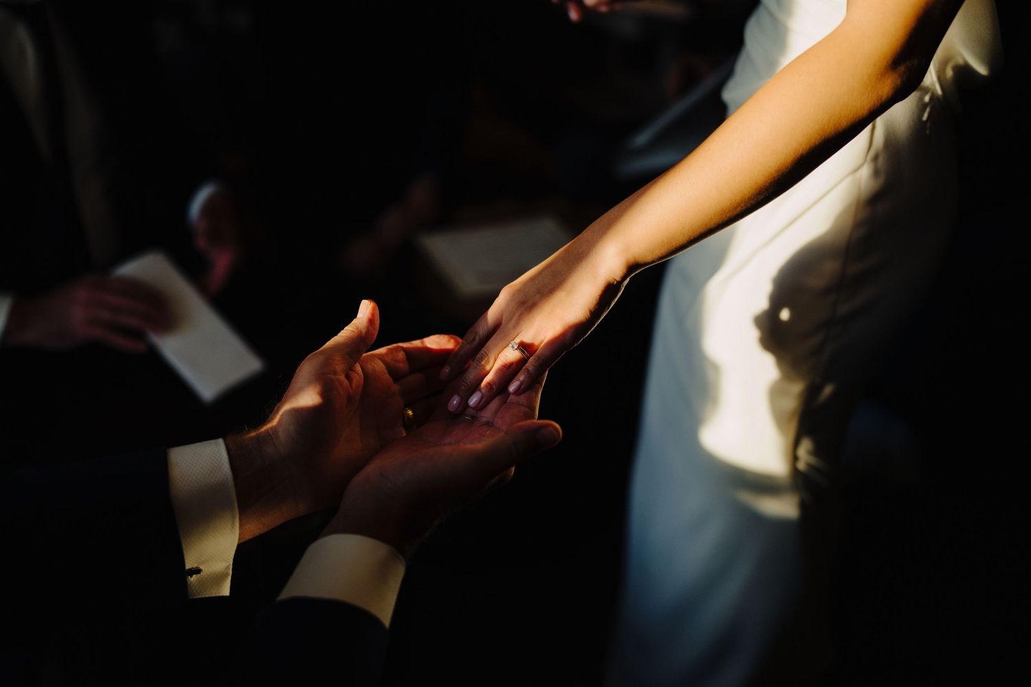 A close-up shot of hands exchanging rings during a wedding ceremony.