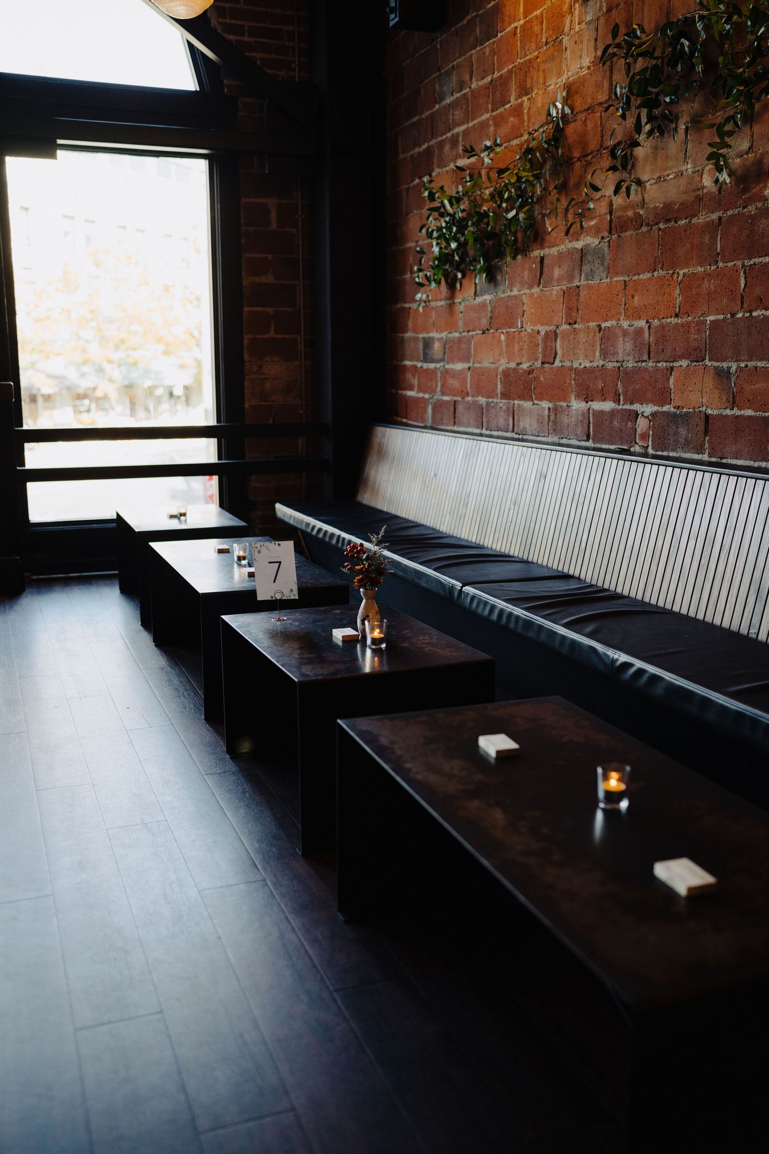 Modern restaurant interior with exposed brick walls and long bench seating.