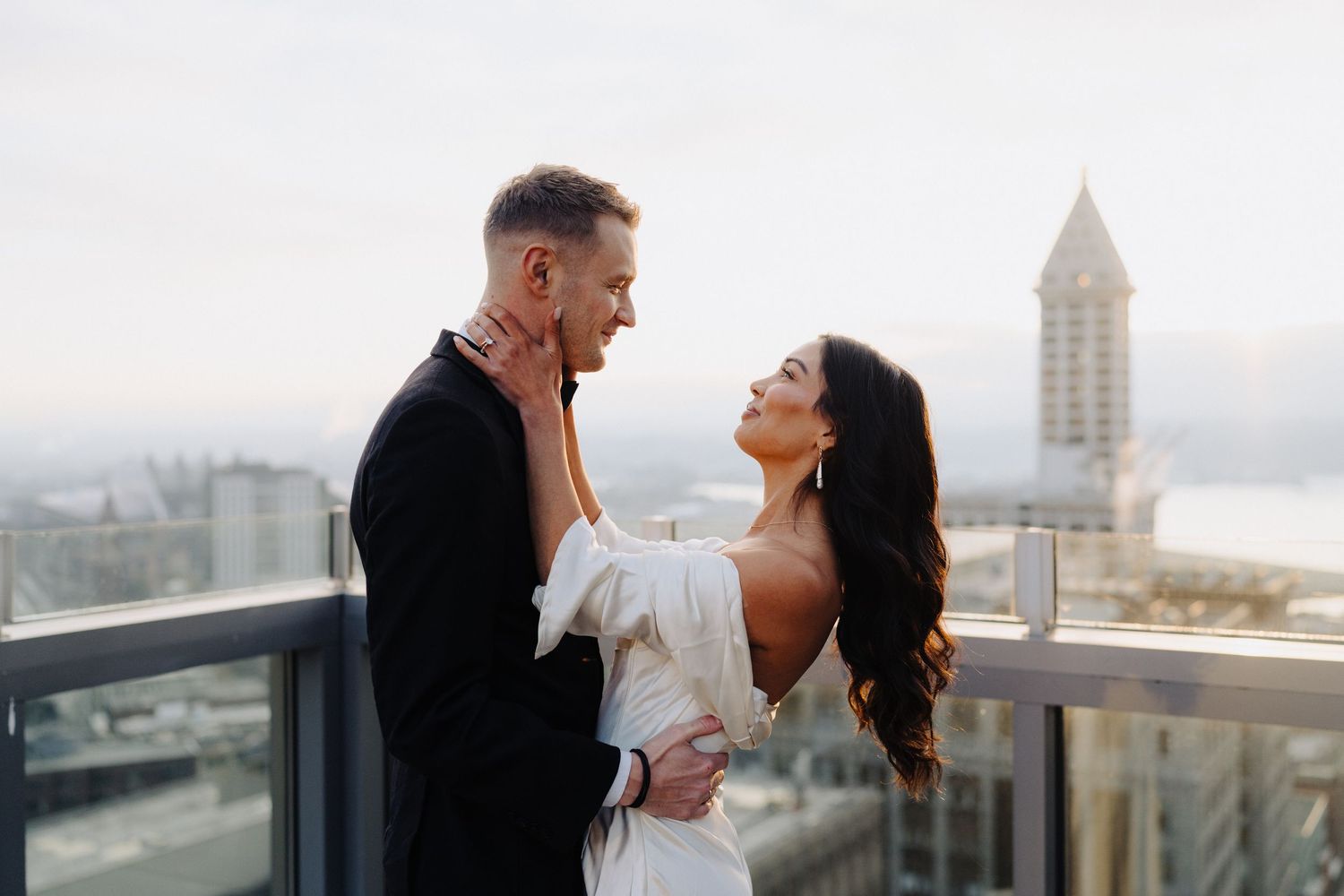 Elegant couple shares an intimate moment on a rooftop terrace with iconic city architecture in background.