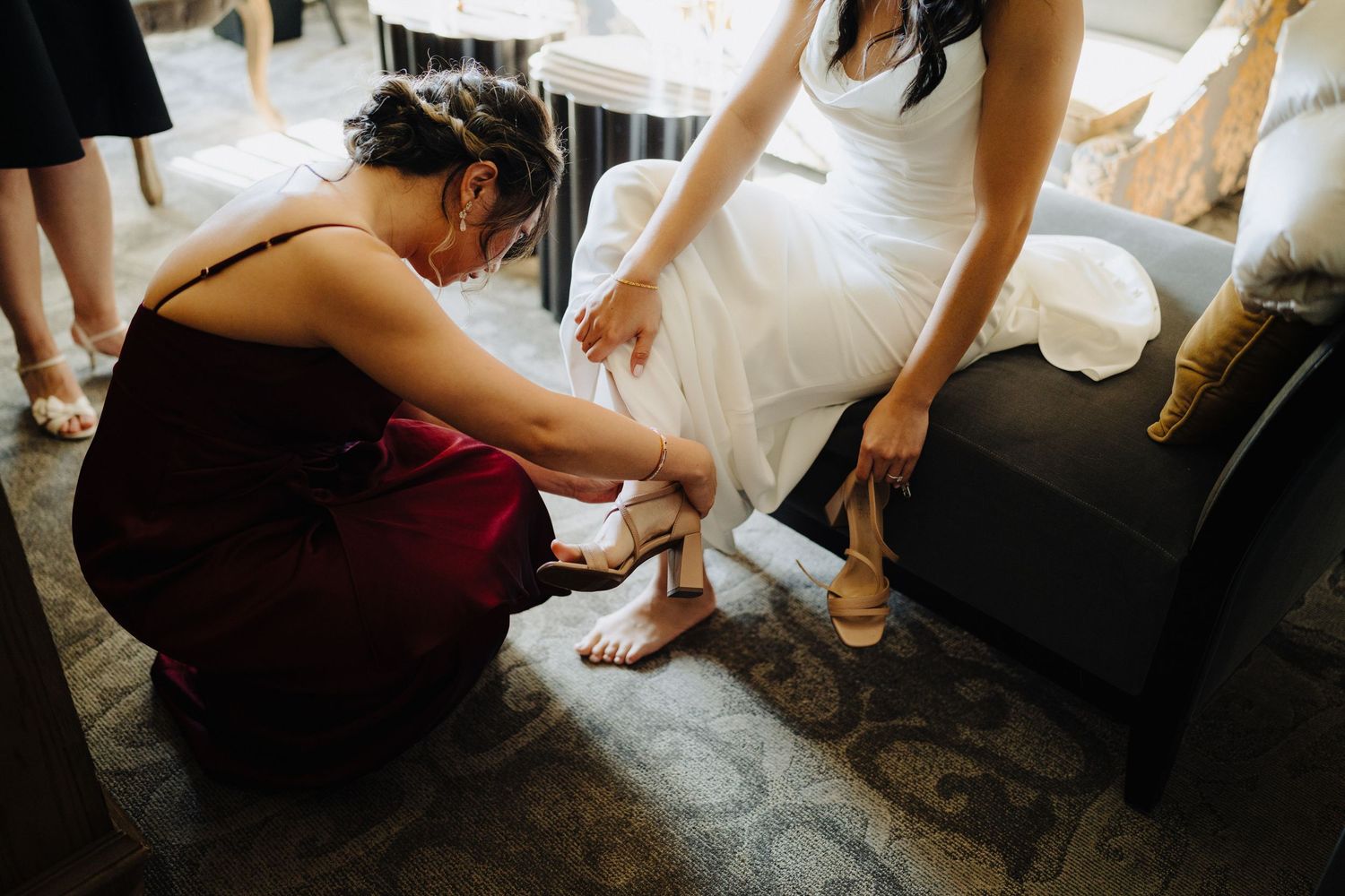 A close-up shot of someone helping adjust formal footwear during wedding preparations.
