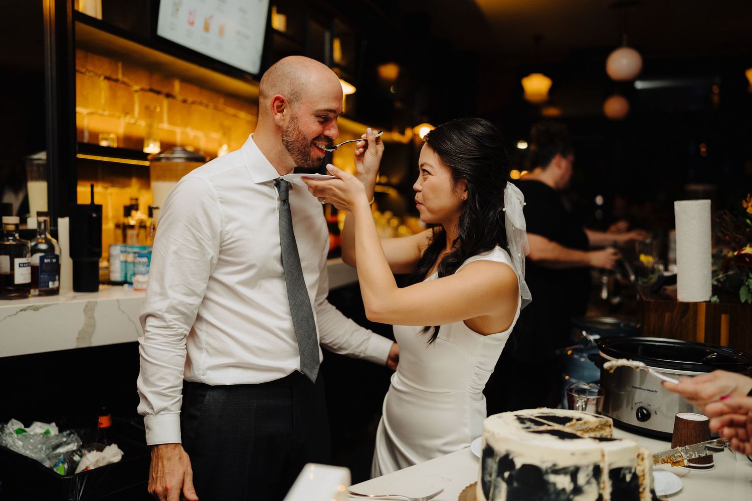 A couple shares a playful moment at the wedding reception bar.