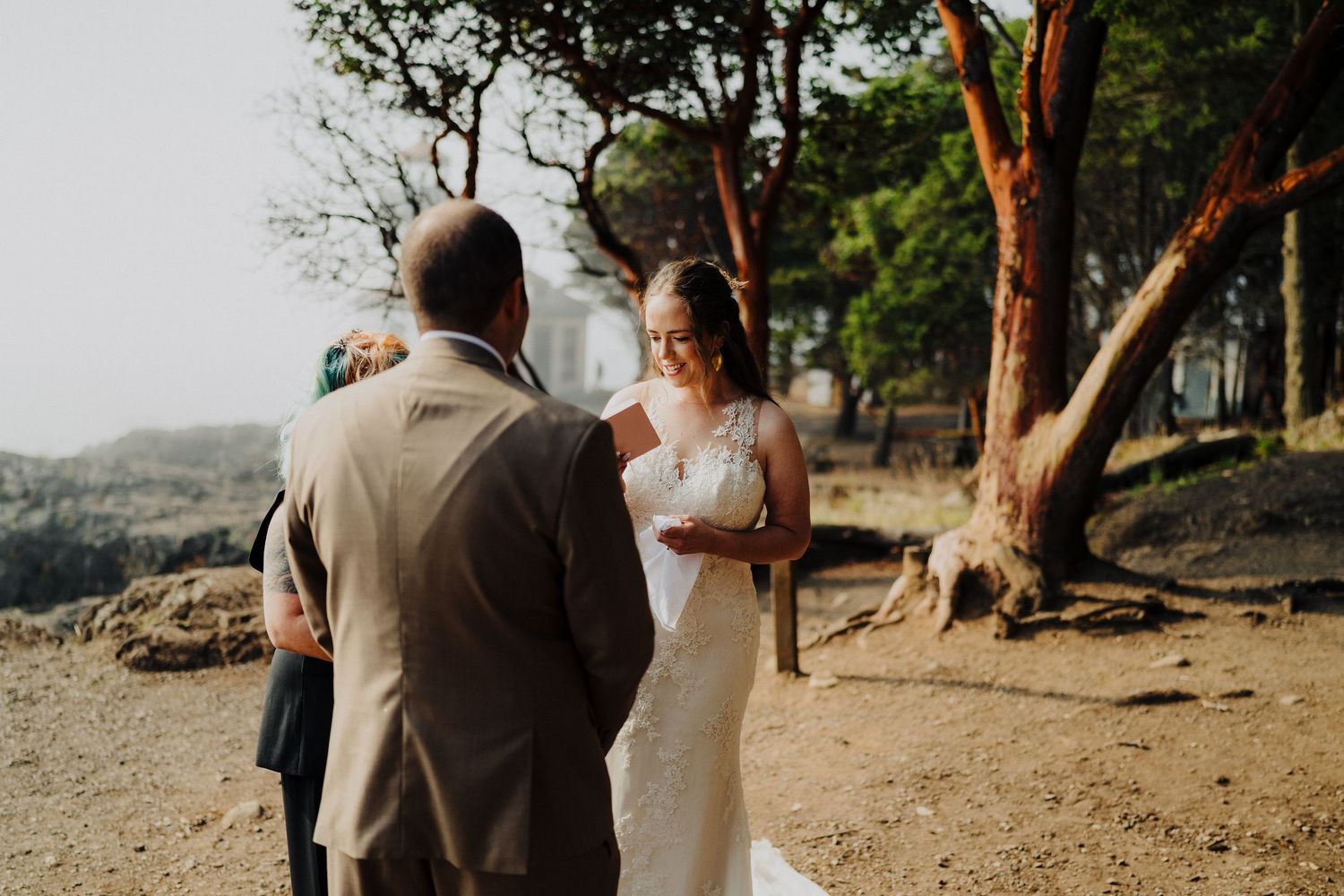 A couple shares an intimate moment during their outdoor wedding ceremony on a scenic hilltop at golden hour.
