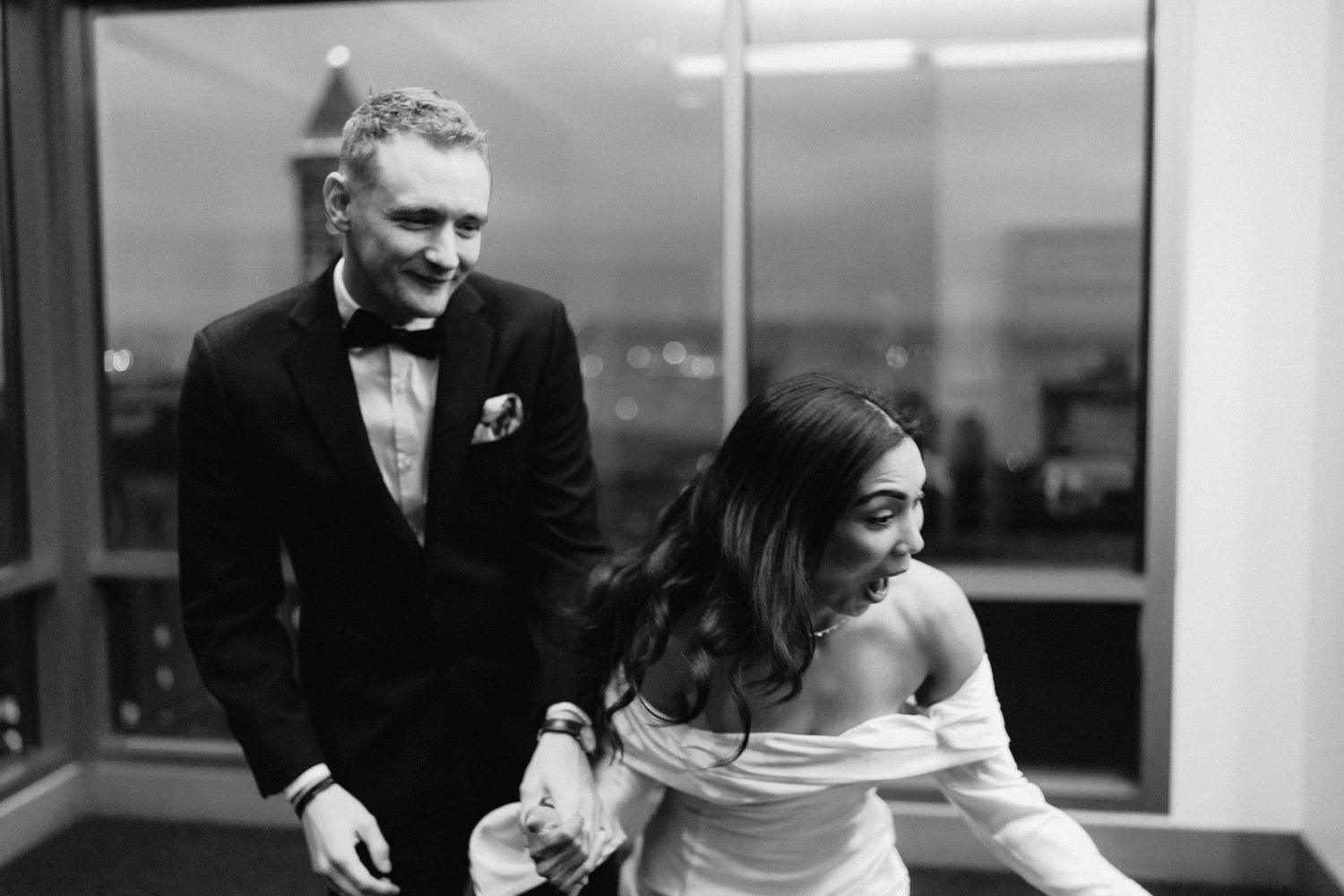 A black and white photo of a couple sharing a playful moment during their wedding ceremony.
