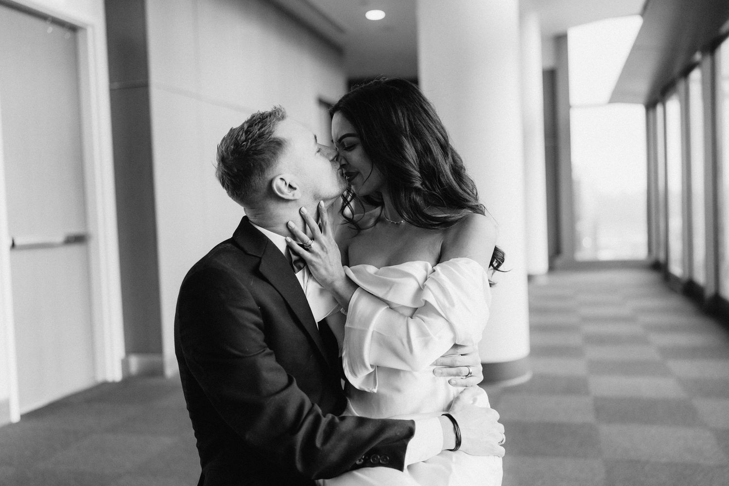 Intimate black and white portrait of couple embracing in modern hallway.