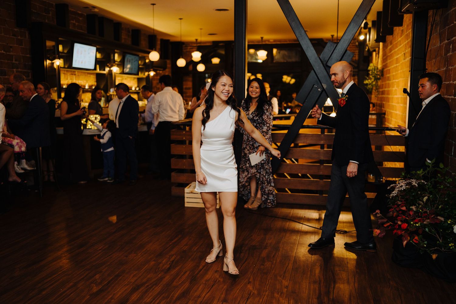 A person in white dress twirls on the dance floor during wedding reception.