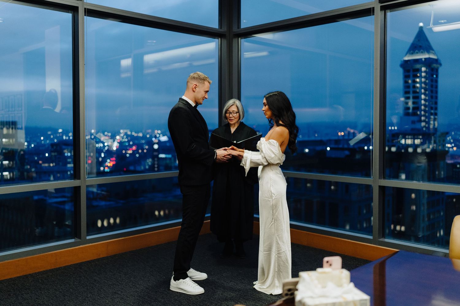 An intimate wedding ceremony in a high-rise building with city lights twinkling in the background.