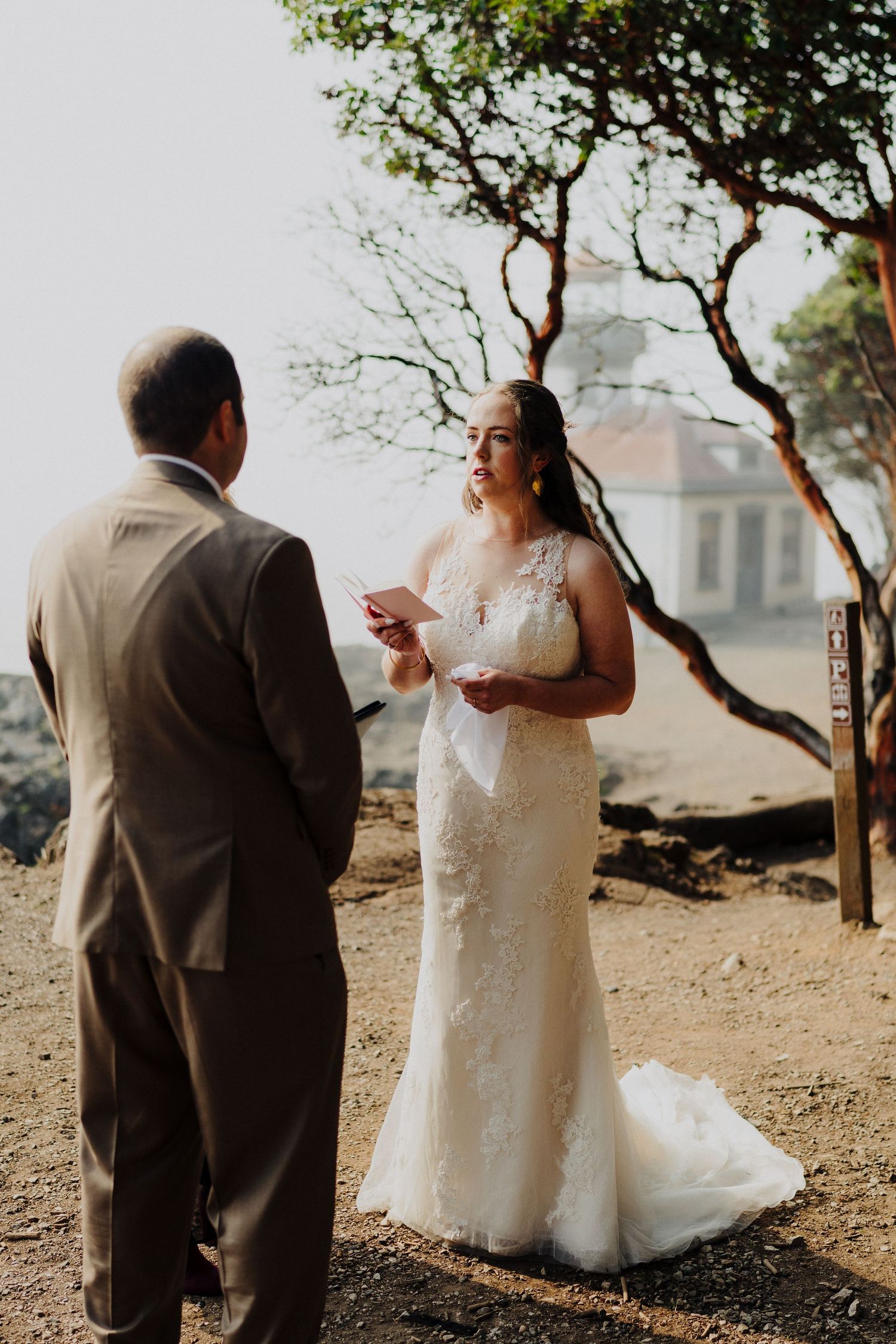 A couple shares their wedding vows during an intimate outdoor ceremony with a scenic backdrop.