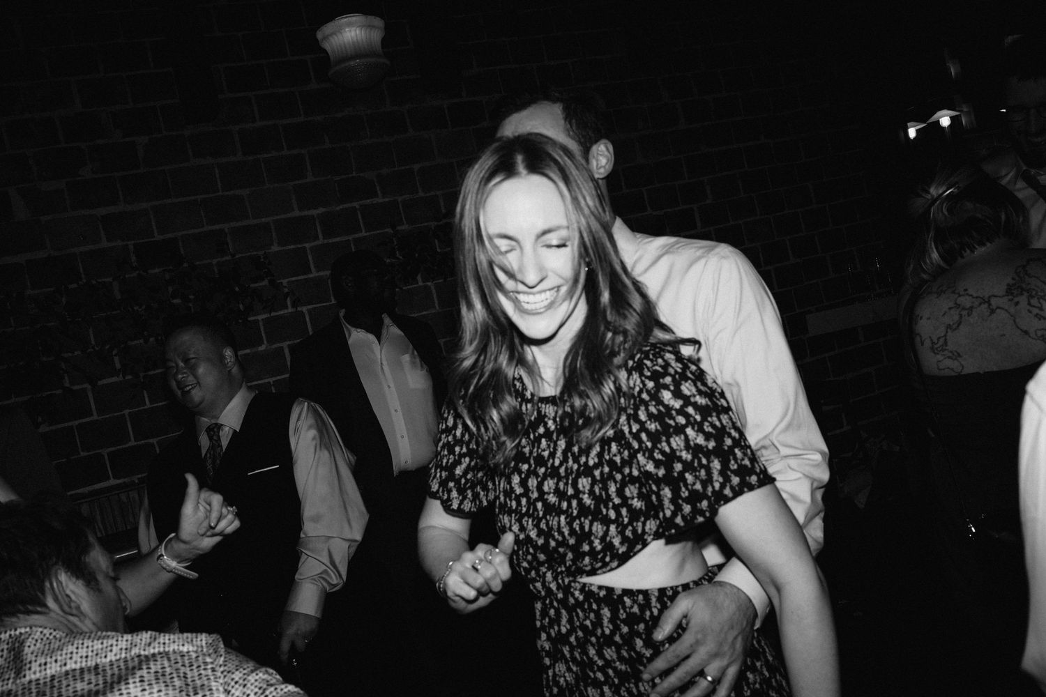 Black and white photo of dancing and celebration at a wedding reception.