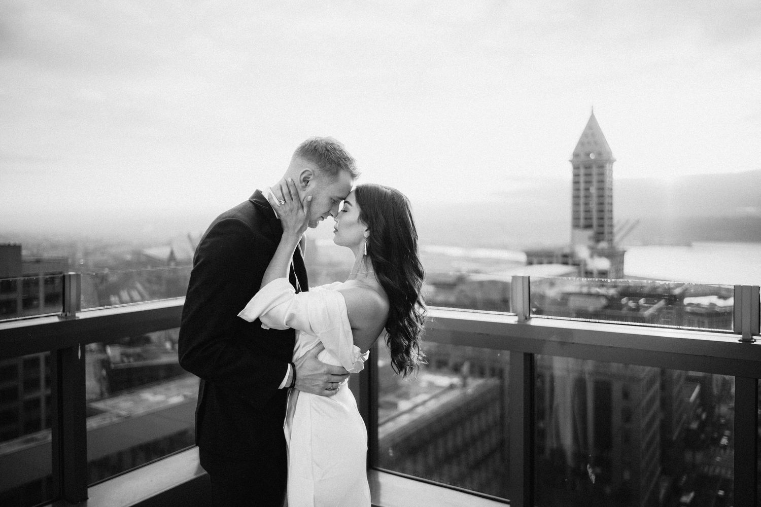 Monochrome wedding photo capturing tender moment between couple with iconic tower in distance.