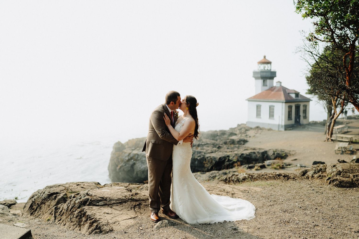 Lighthouse perched on rocky cliffs overlooking the ocean during a coastal wedding ceremony.