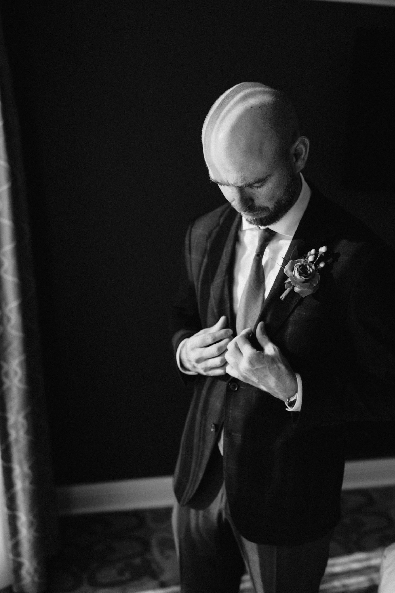 Formal attire being adjusted in a dark room with dramatic lighting.