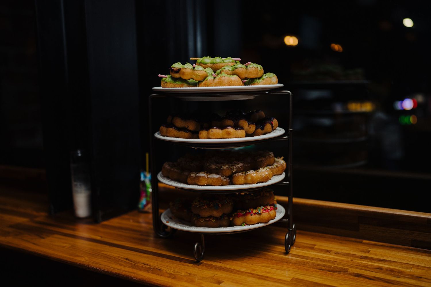 A multi-tiered platter of appetizers displayed on a wooden surface in dim lighting.