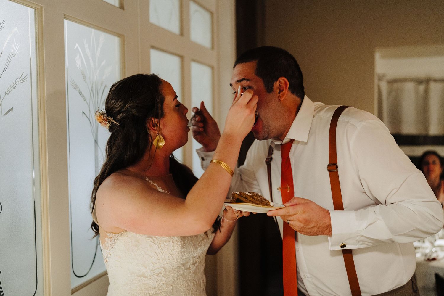 Newlyweds playfully feed each other cake at their wedding reception.