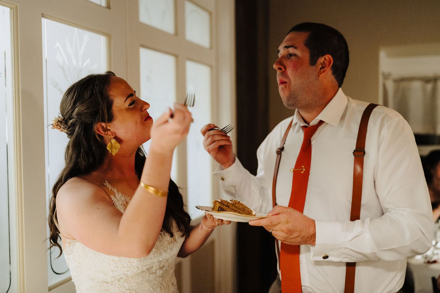 Playful moment of newlyweds feeding each other cake during their wedding reception.