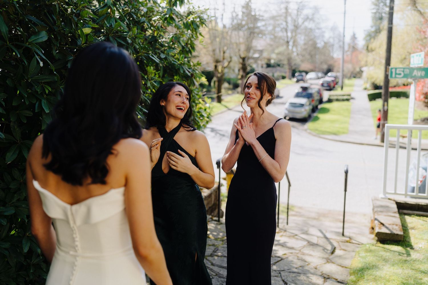 Three smiling figures share an emotional moment together outdoors while wearing formal attire.