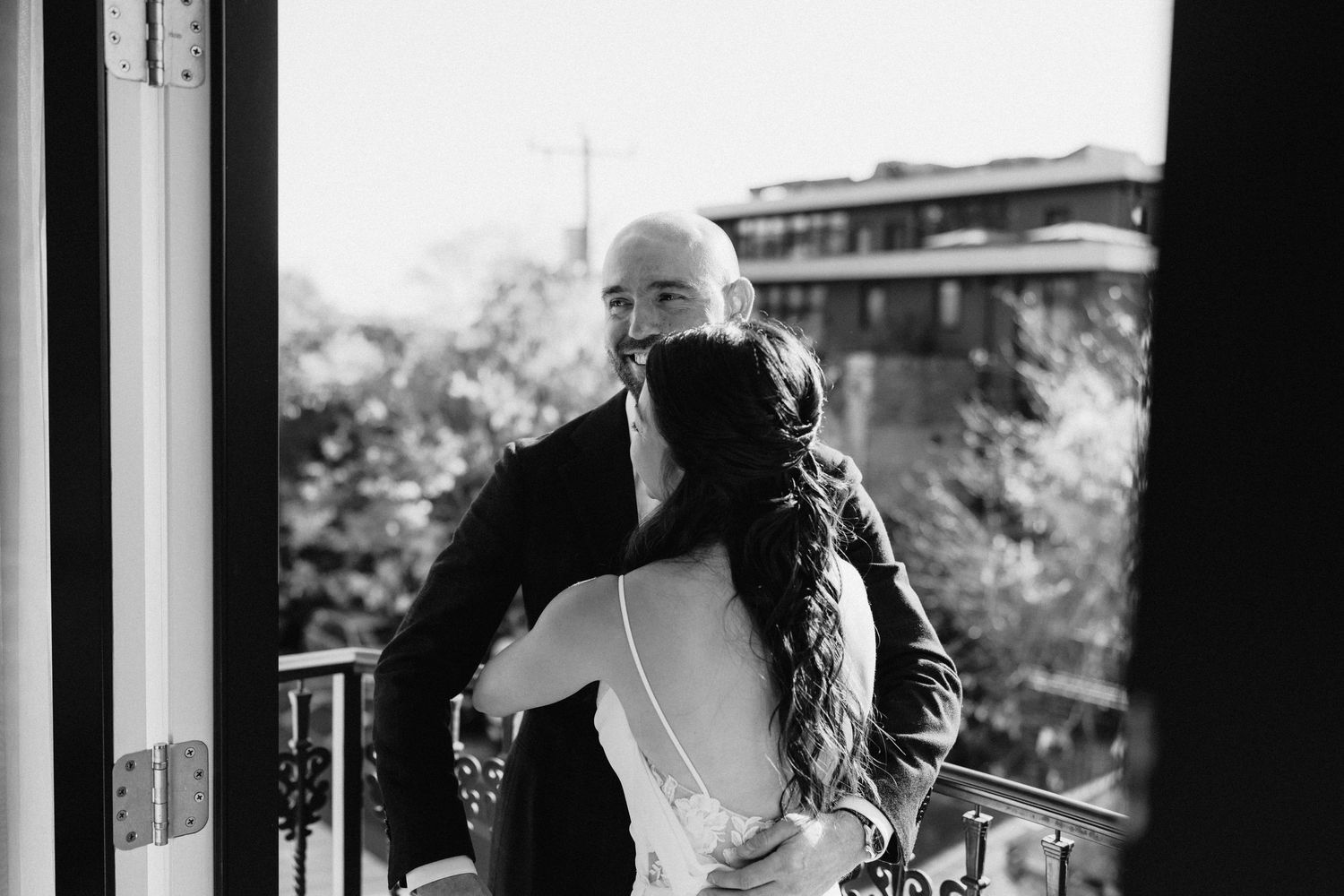 A black and white wedding portrait shows a couple embracing in front of a scenic backdrop.