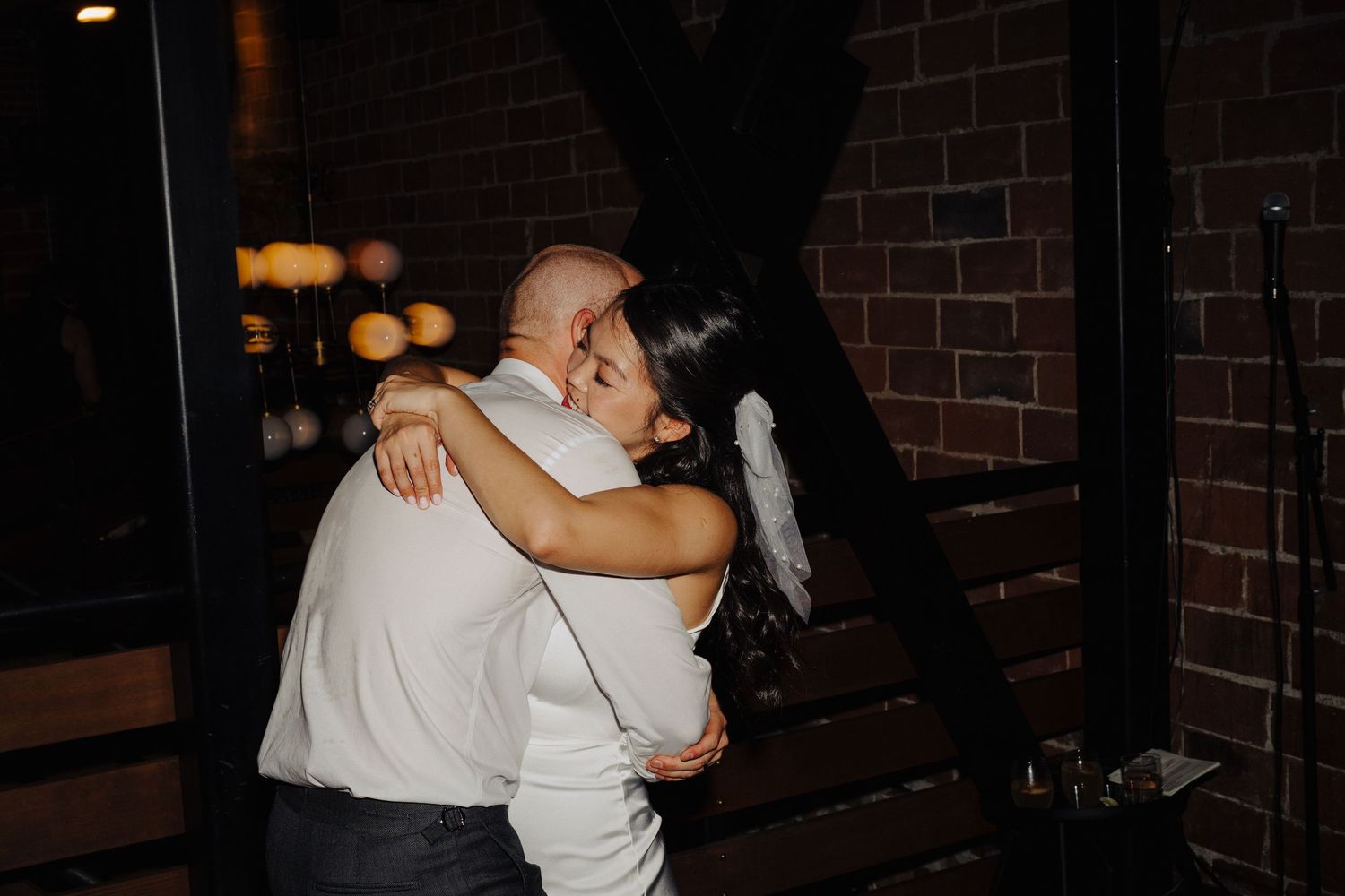 A tender moment between a couple sharing a dance in dim lighting.