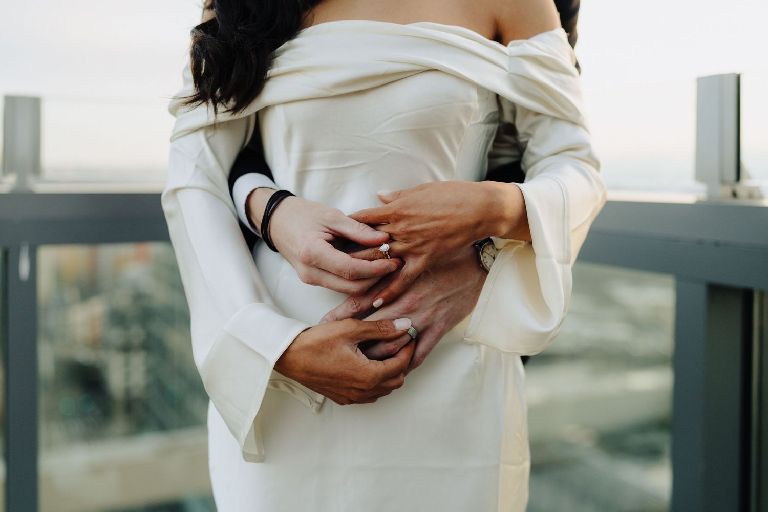 Close-up of couple's embrace showing elegant white wedding dress details.