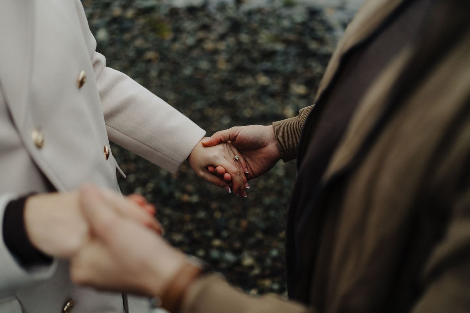 Close-up shot of hands clasped together against a dark rocky background.
