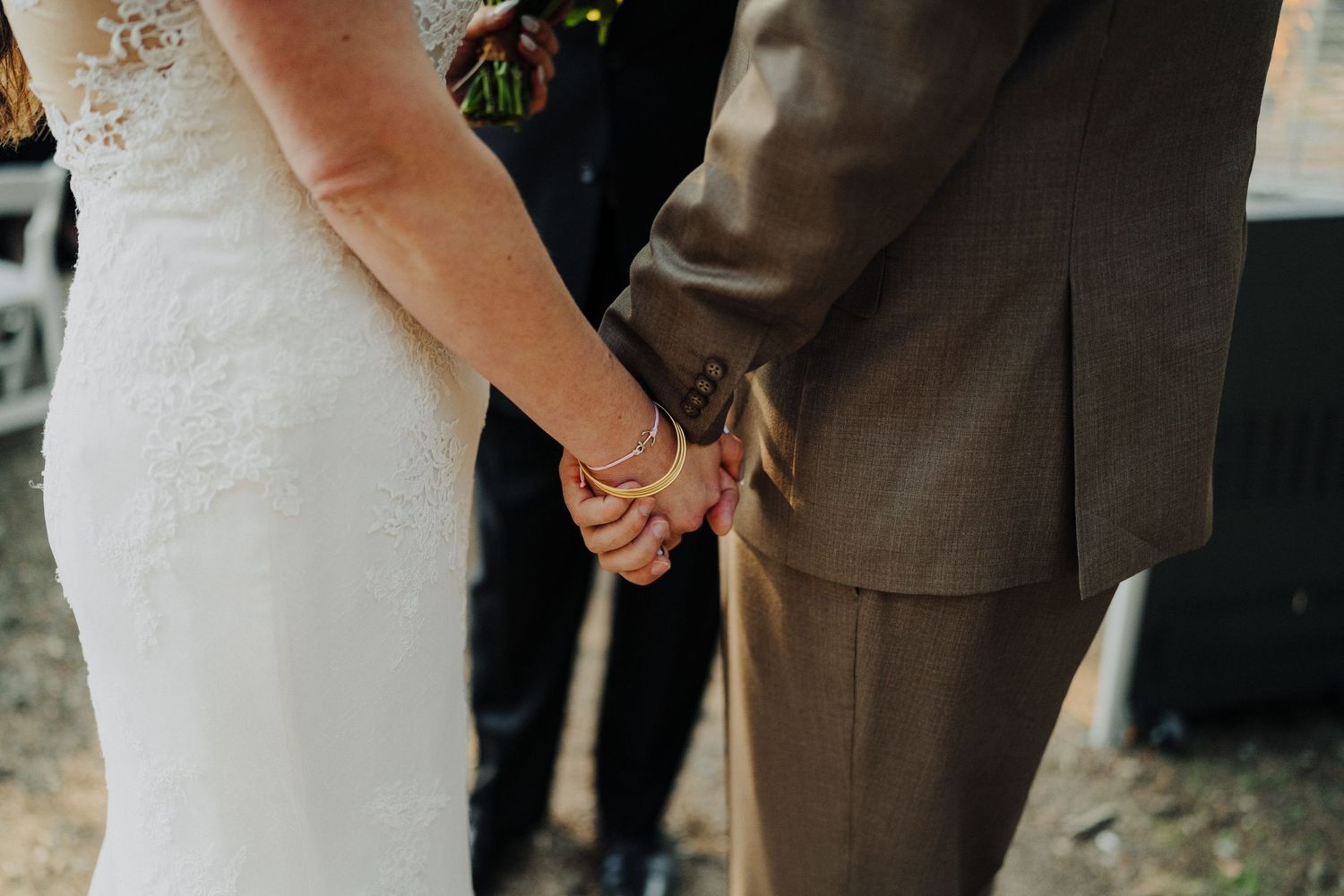 A close-up shot of newlyweds holding hands during their wedding ceremony.
