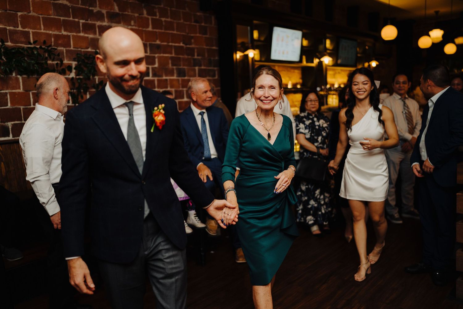 Wedding guests dancing and celebrating on a wooden dance floor.