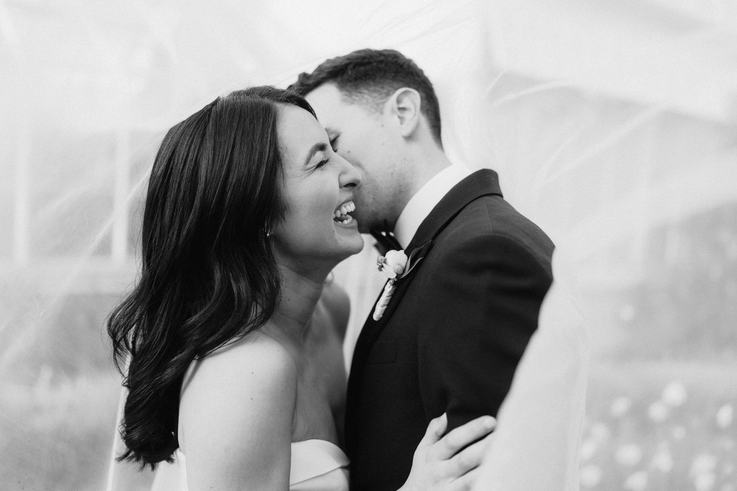 A romantic black and white photo of a couple sharing an intimate moment during their wedding day.