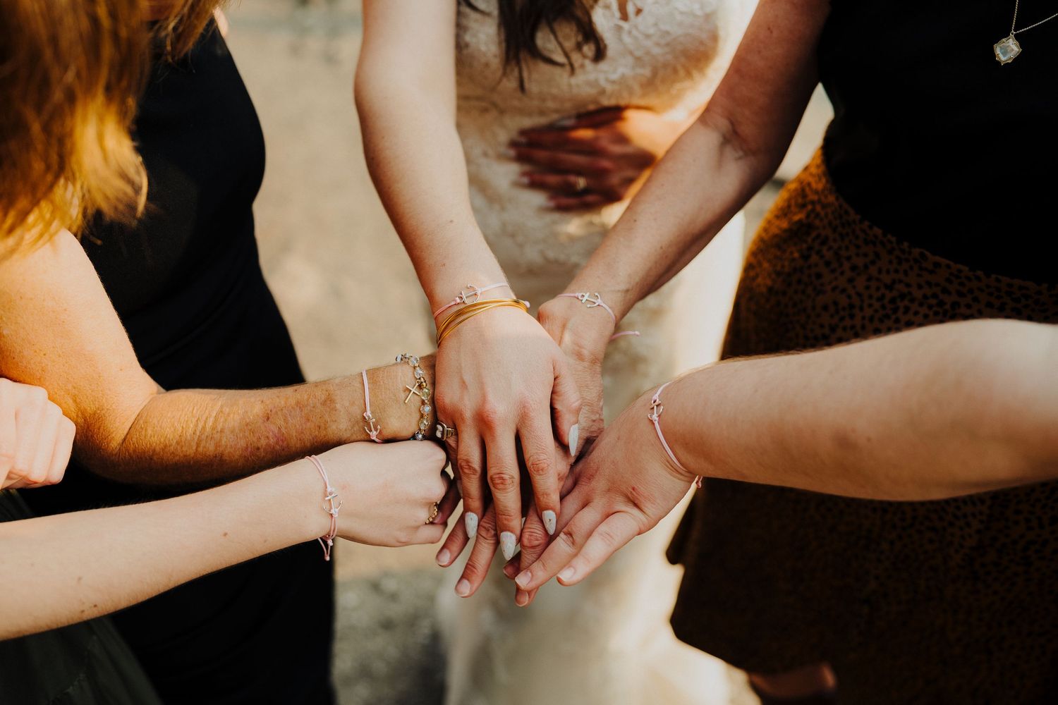 Close-up of hands joining together in a circle, showing unity and connection during a wedding celebration.