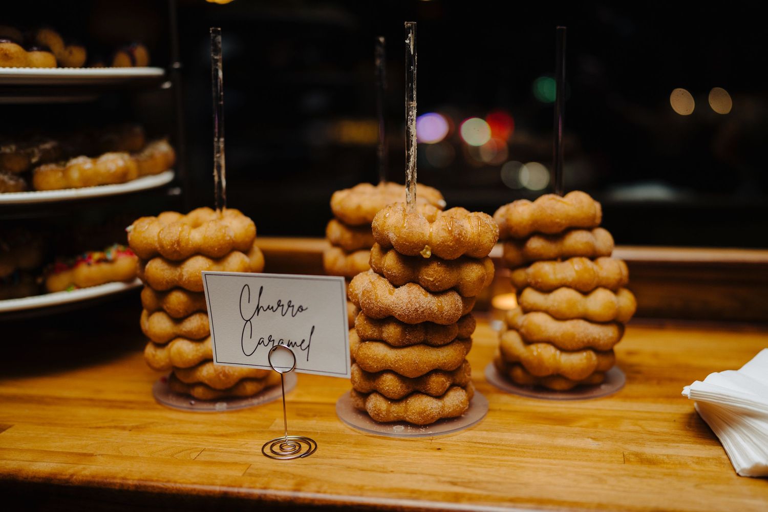 Stacks of donut towers displayed on wooden surface with name card.