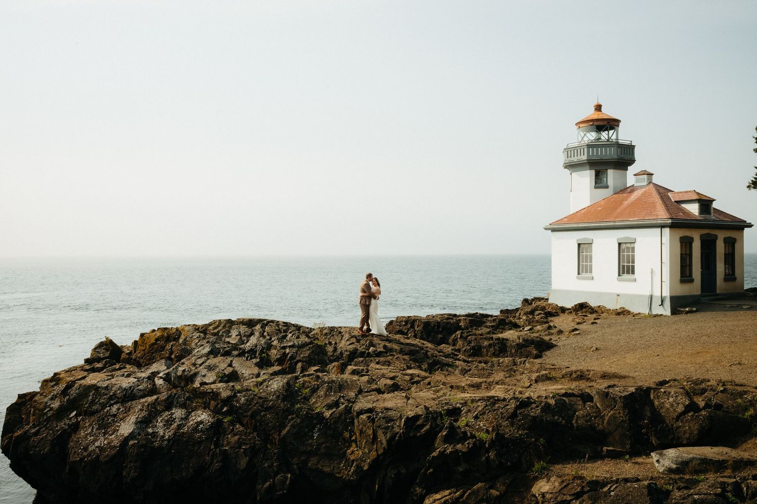 A white lighthouse stands majestically on rocky coastal cliffs above the Pacific ocean.