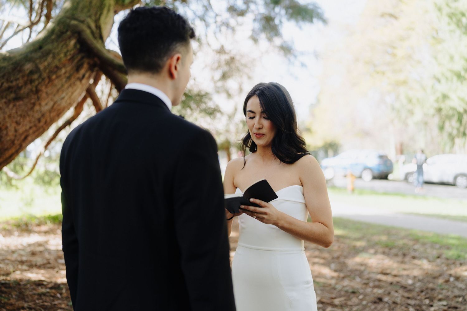 A wedding couple exchanging vows or rings during an intimate outdoor ceremony.