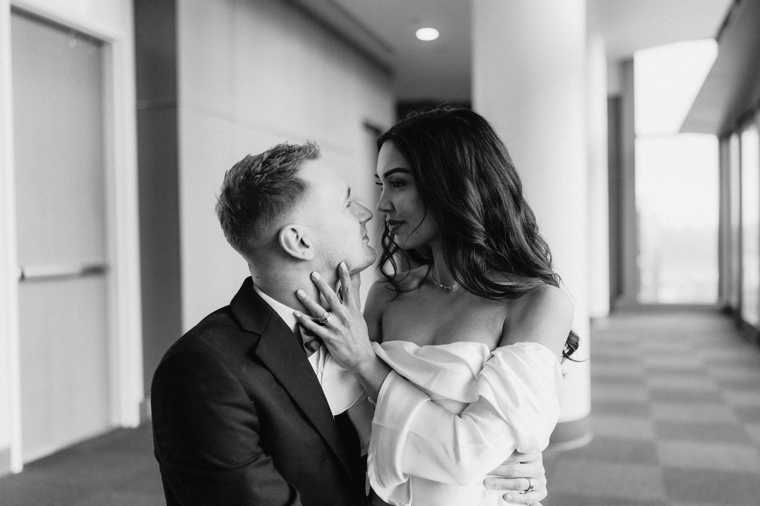 A romantic black and white portrait of a couple sharing an intimate moment in a hallway.