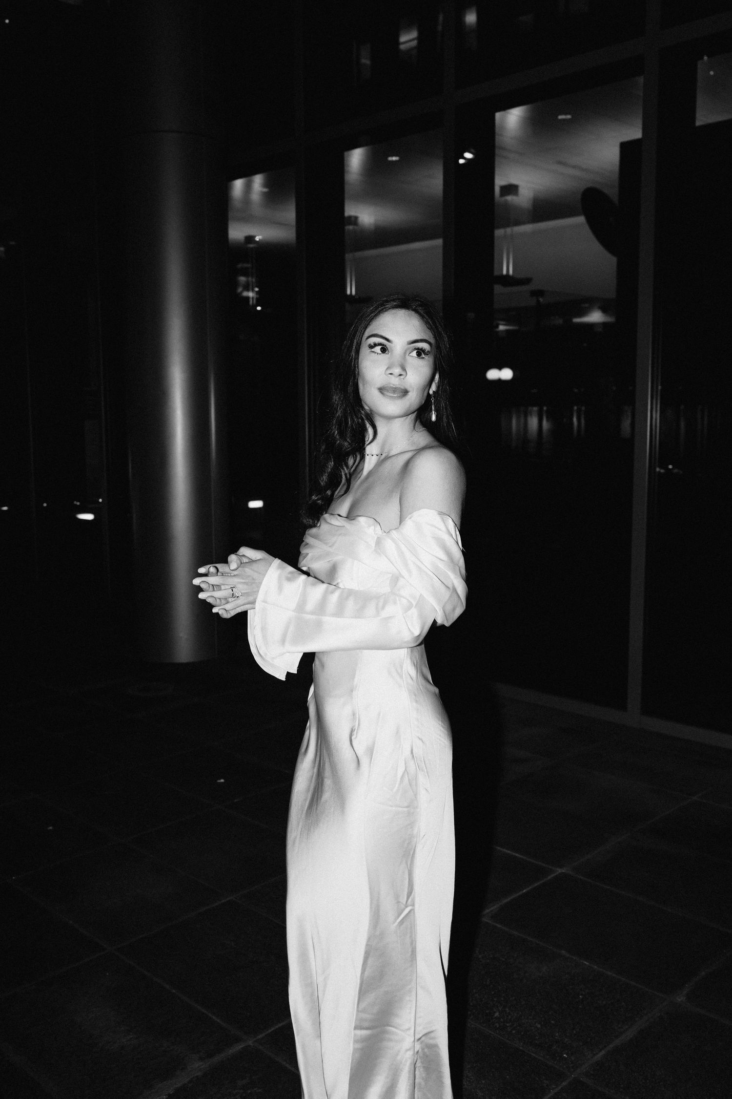 Black and white portrait of bride in elegant off-shoulder gown with bell sleeves.