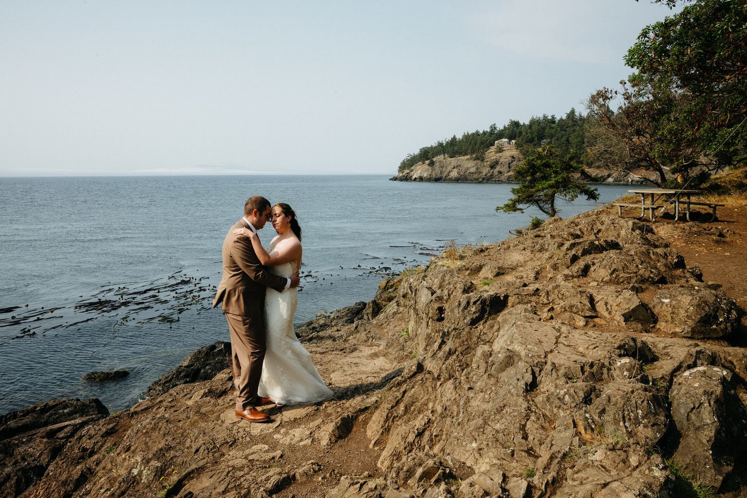 A romantic coastal wedding portrait on rocky cliffs overlooking the Pacific Ocean.