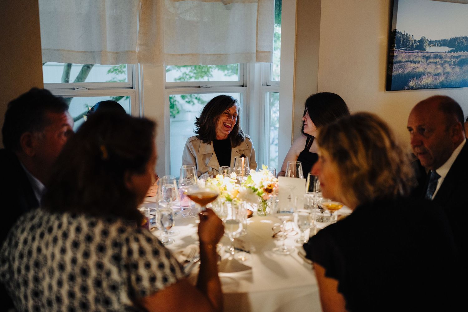 Dinner guests gathered around an elegant table set with wine glasses and white linens for an intimate dining experience.