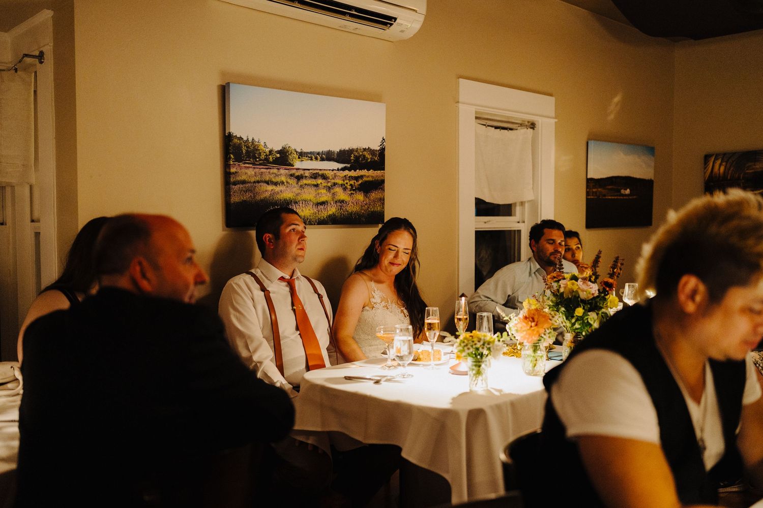Candlelit wedding reception dinner with guests seated at tables in an intimate indoor setting.
