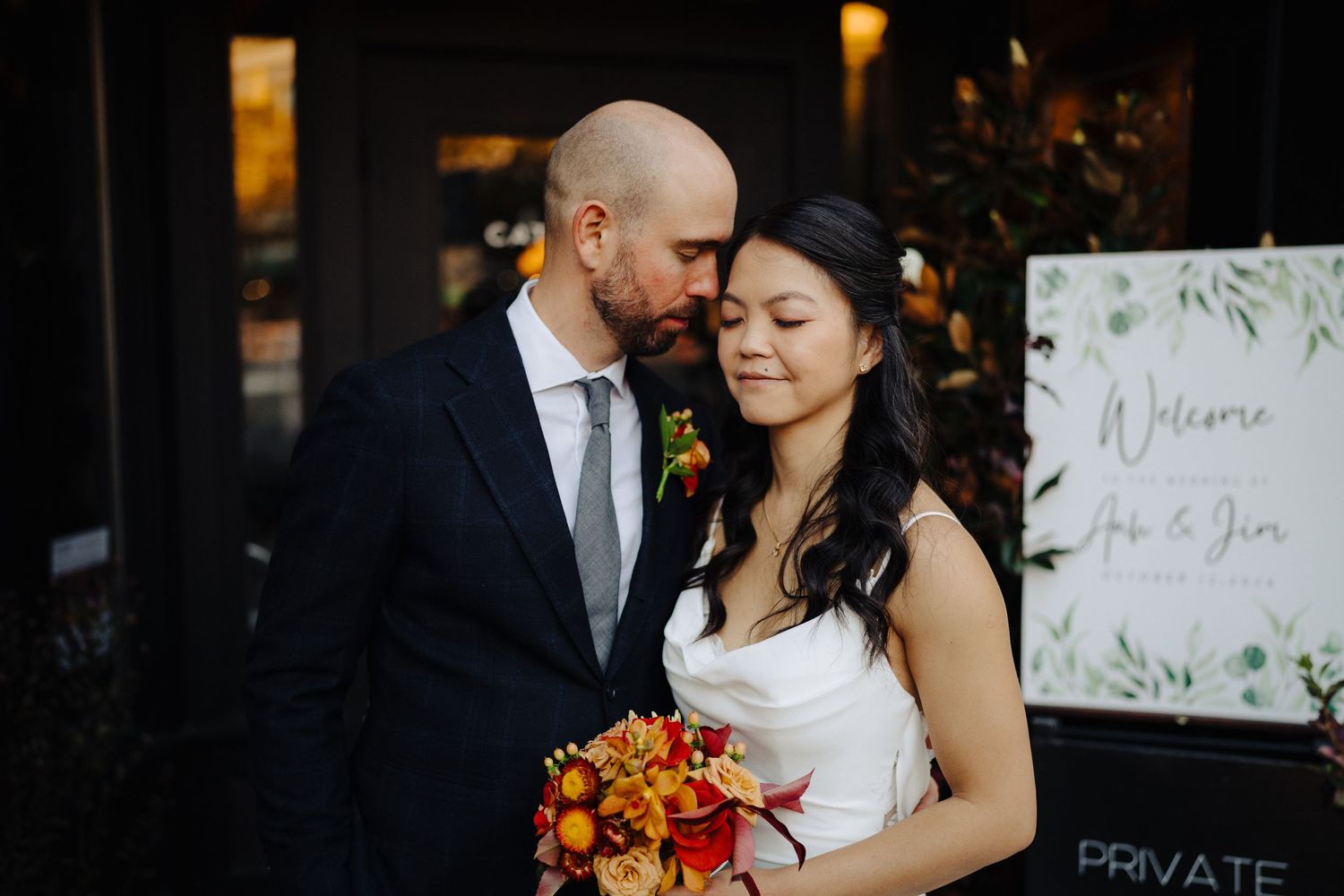 Wedding couple sharing intimate moment with autumn bouquet.