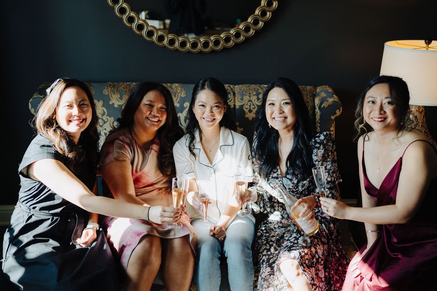 A group toasts with champagne glasses while sitting on an elegant couch at a celebration.