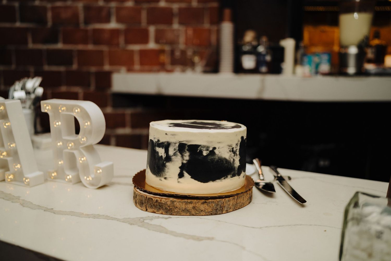 Black and white wedding cake displayed on wooden stand with decorative letters.