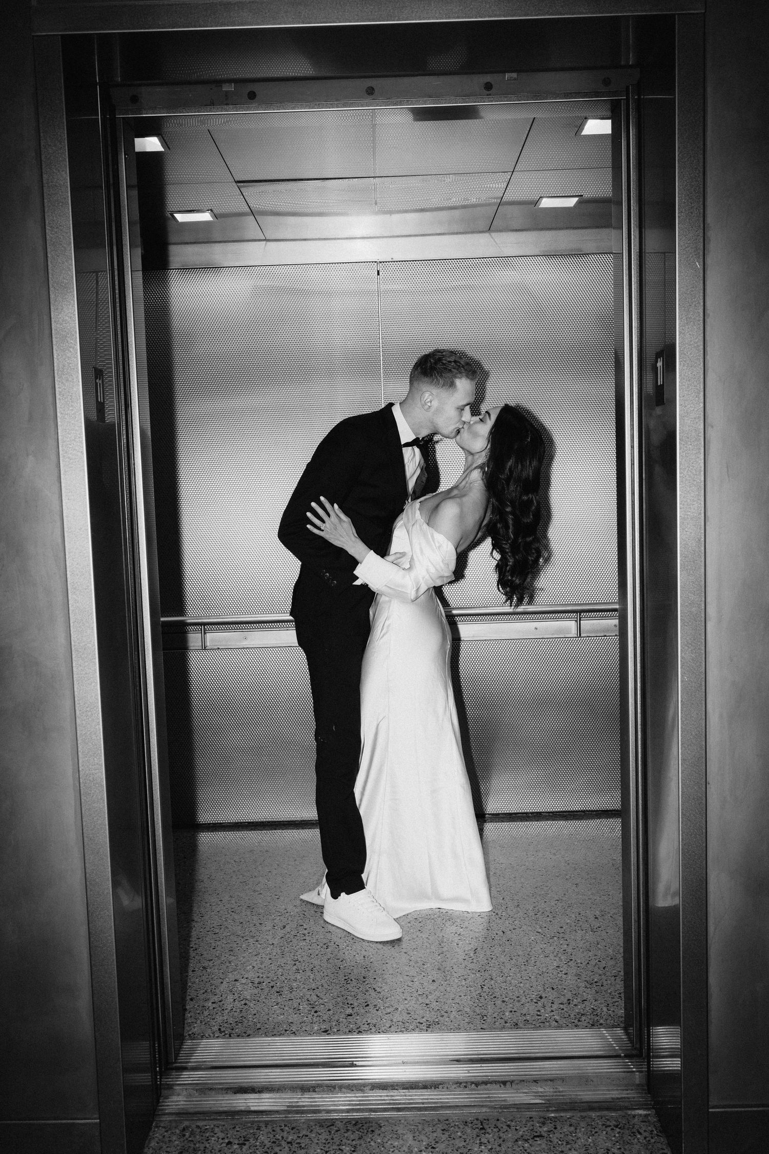Black and white wedding photo capturing intimate moment between couple in elevator.