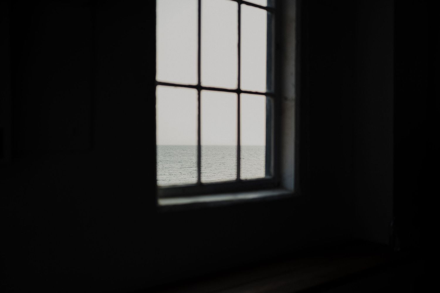 A minimalist window frame silhouetted against a bright seascape view.