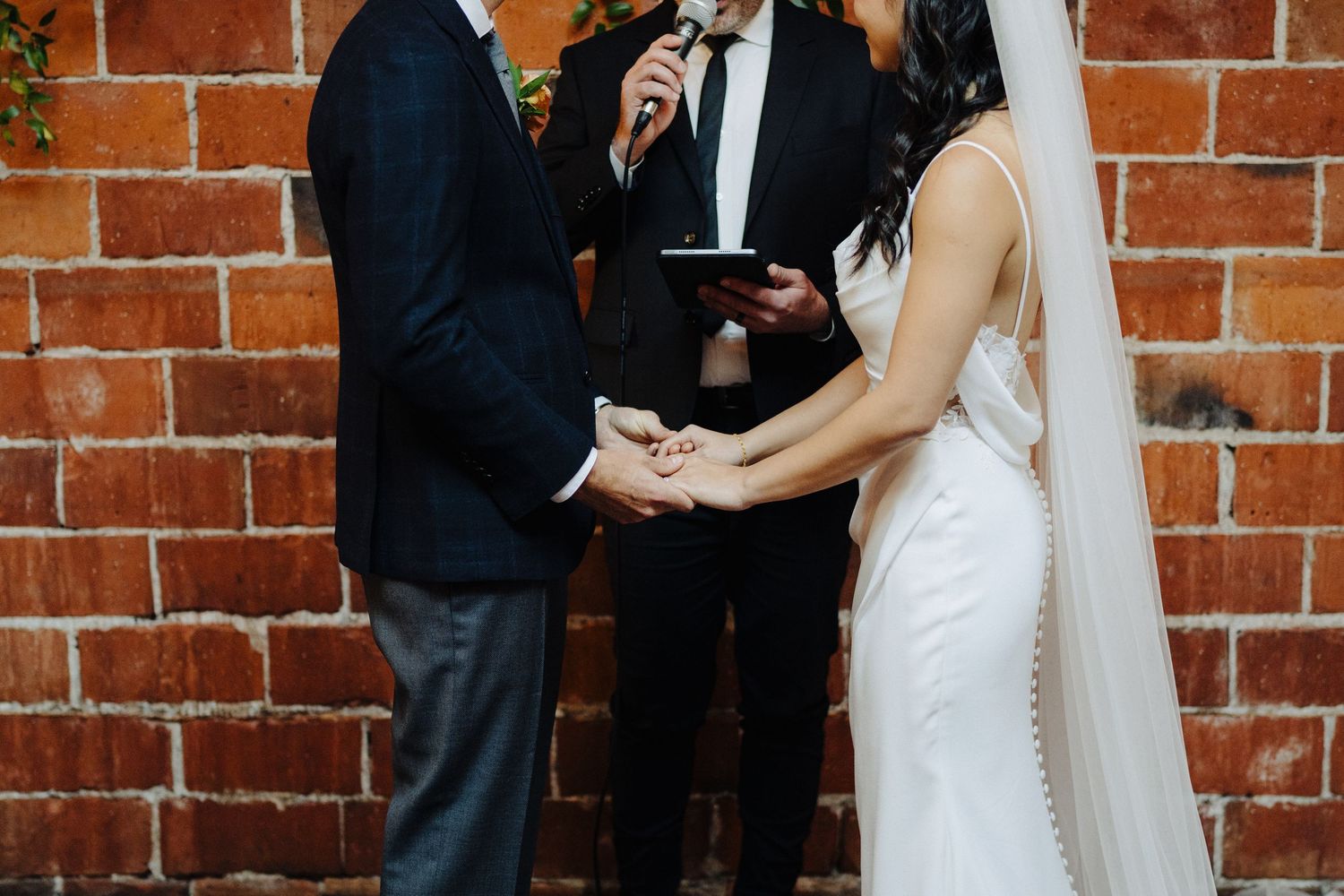 Wedding ceremony taking place against a rustic brick wall backdrop.